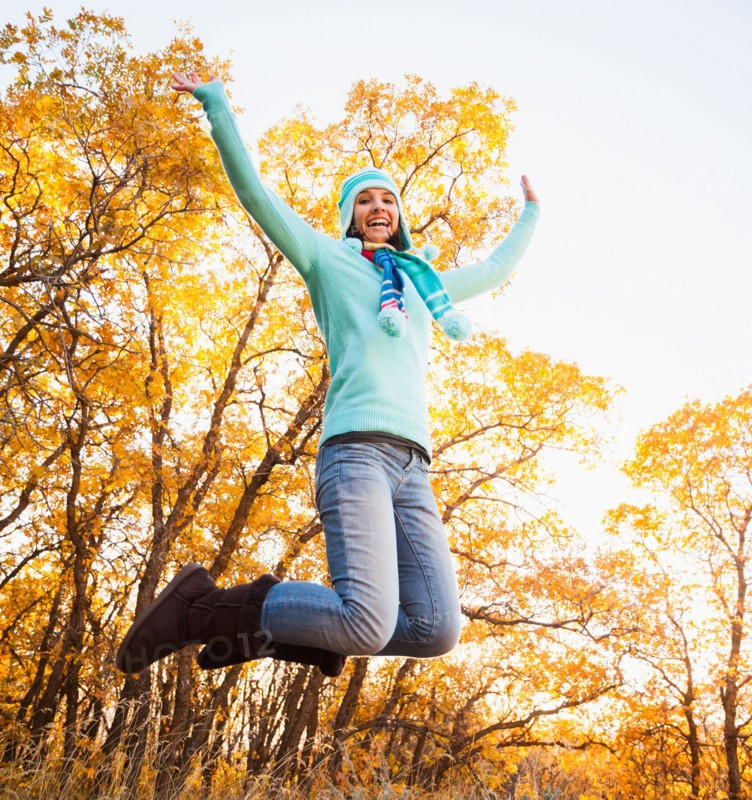Happy young woman jumping in autumn forest. Photo : Mike Kemp
