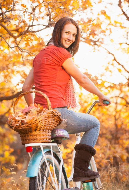 Happy young woman with bicycle in autumn in forest. Photo : Mike Kemp