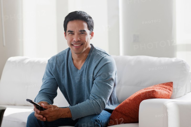 Portrait of smiling mid adult man sitting on sofa. Photo : Dan Bannister