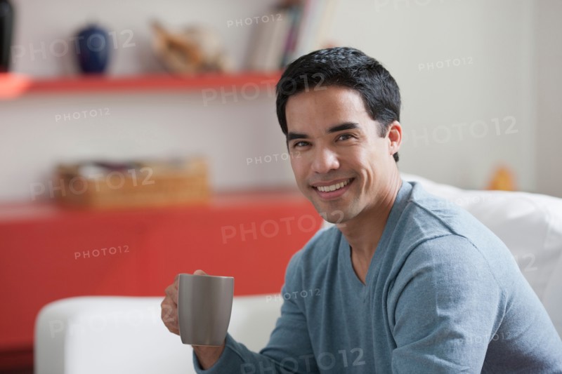 Portrait of man drinking coffee in living room. Photo: Dan Bannister