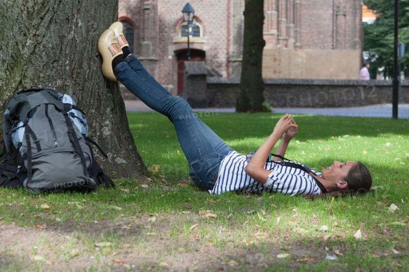 Young woman with backpack lying on grass. Photo: Jan Scherders