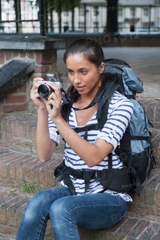 Portrait of young woman with backpack and camera. Photo : Jan Scherders