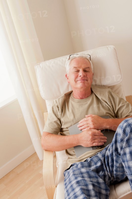 Senior man taking nap and holding book. Photo : Rob Lewine