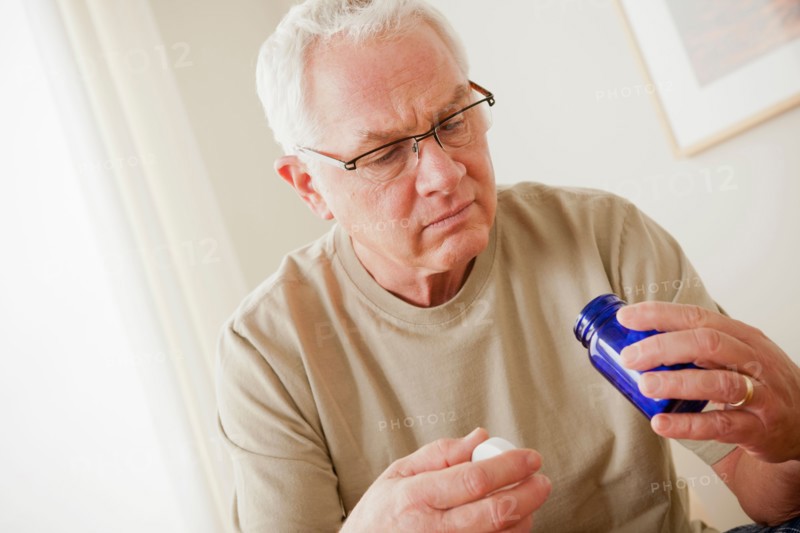 Senior man holding medicine flask. Photo : Rob Lewine