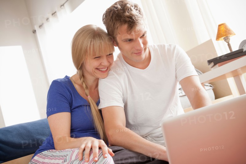 Couple sitting on floor using laptop. Photo : Rob Lewine