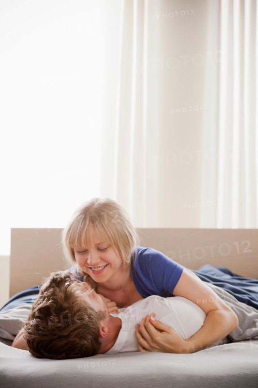 Woman lying atop man in bed. Photo: Rob Lewine