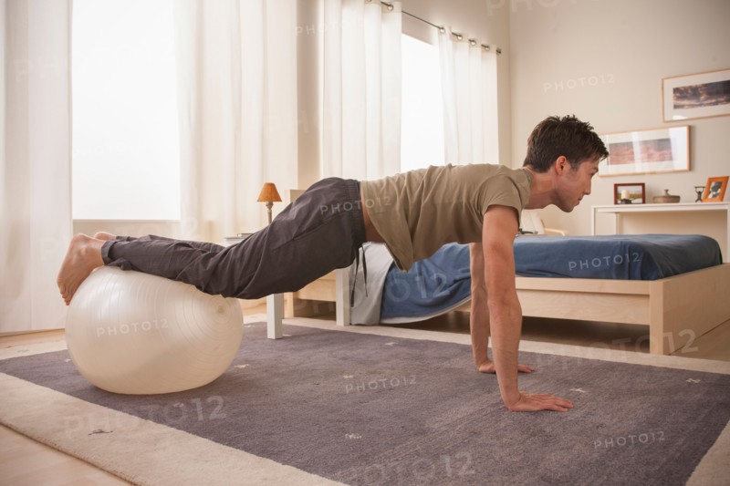 Man doing yoga using fitness ball. Photo : Rob Lewine
