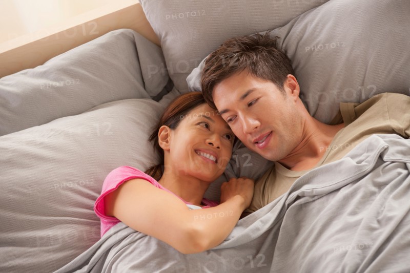 Portrait of couple lying in bed. Photo: Rob Lewine