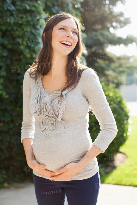 Pregnant mid adult woman standing in front of entrance door. Photo : Jessica Peterson
