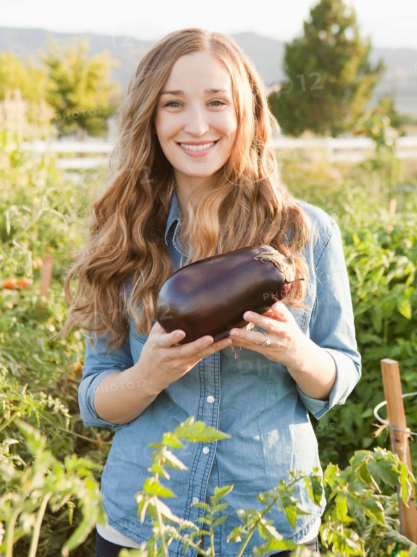 Portrait of young woman holding eggplant. Photo : Jessica Peterson