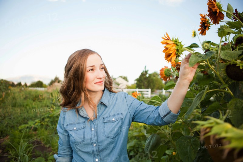 Portrait of young woman harvesting sunflowers. Photo : Jessica Peterson