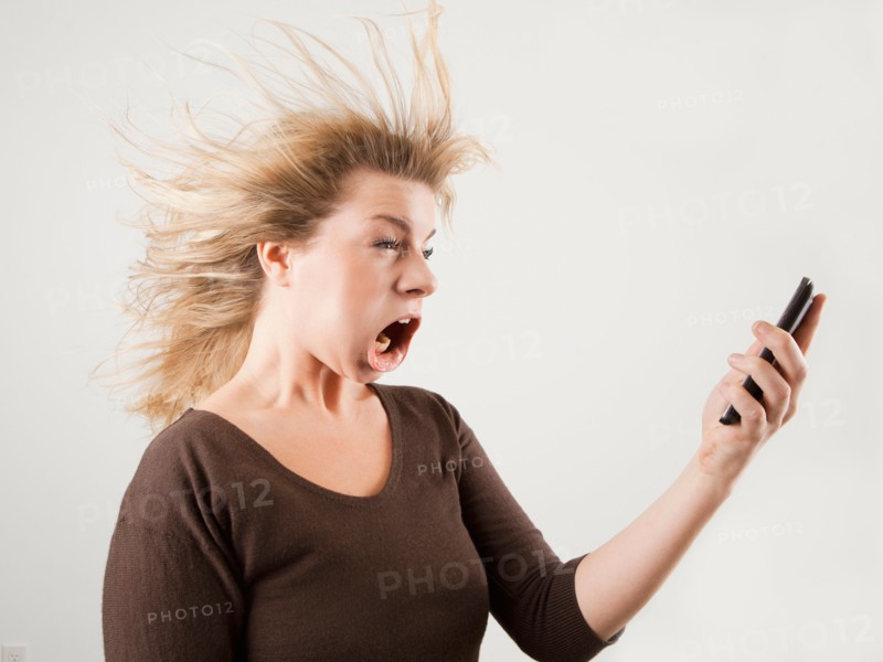 Studio shot of woman with windblown mouth holding phone. Photo: Jessica Peterson
