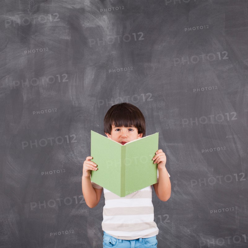 Studio shot of boy (6-7) reading. Photo : Jessica Peterson