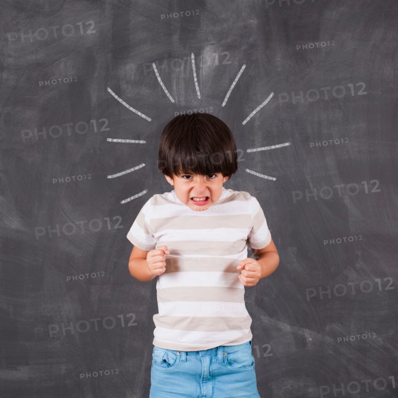 Studio portrait of boy (6-7) in front of blackboard. Photo : Jessica Peterson