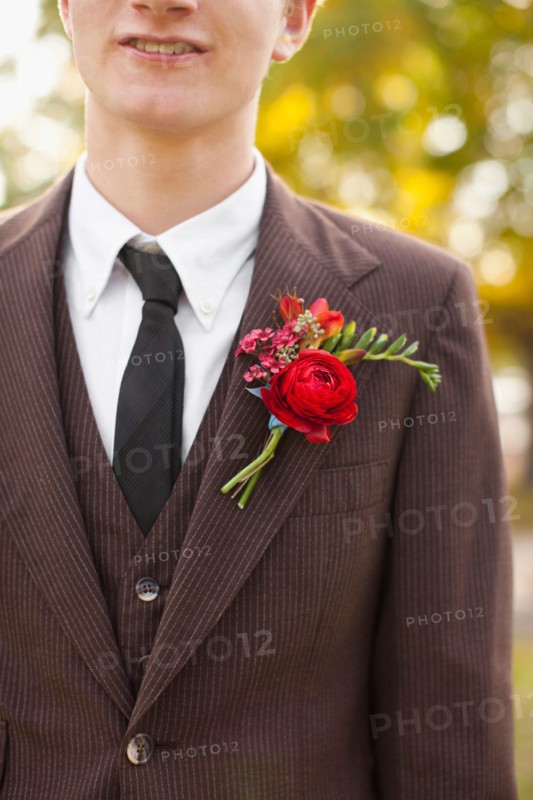 Mid section of groom wearing full suit decorated with boutonniere. Photo: Jessica Peterson