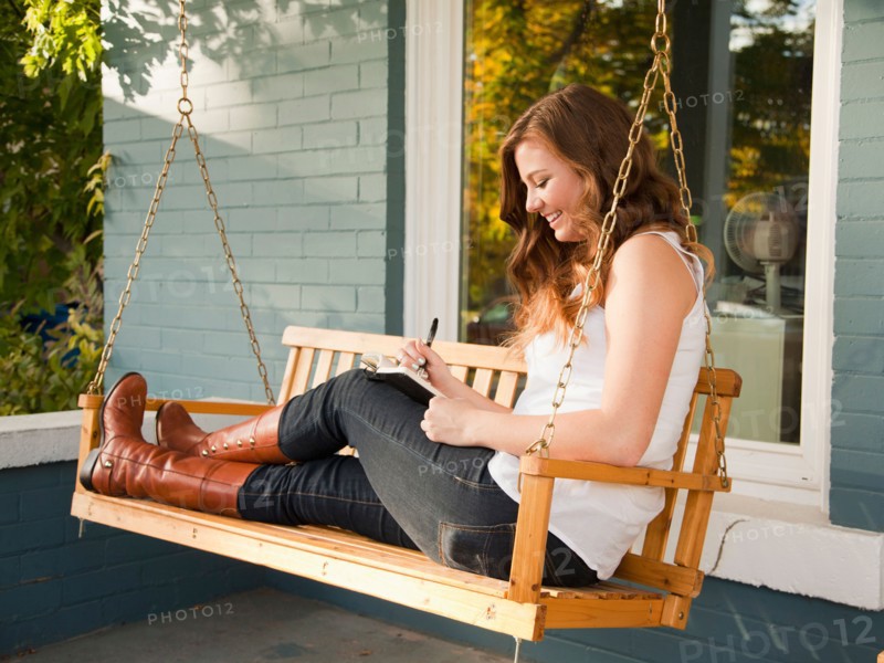 Young woman sitting on swing and making notes. Photo: Jessica Peterson