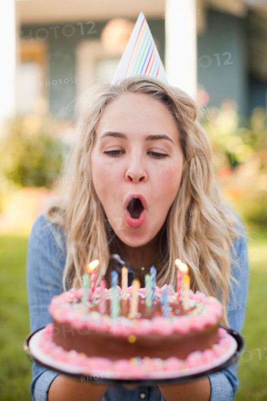 Portrait of young woman blowing birthday candles. Photo : Jessica Peterson