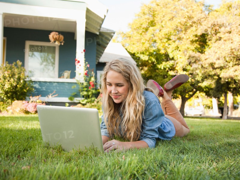 Young woman lying down on grass with her laptop. Photo : Jessica Peterson