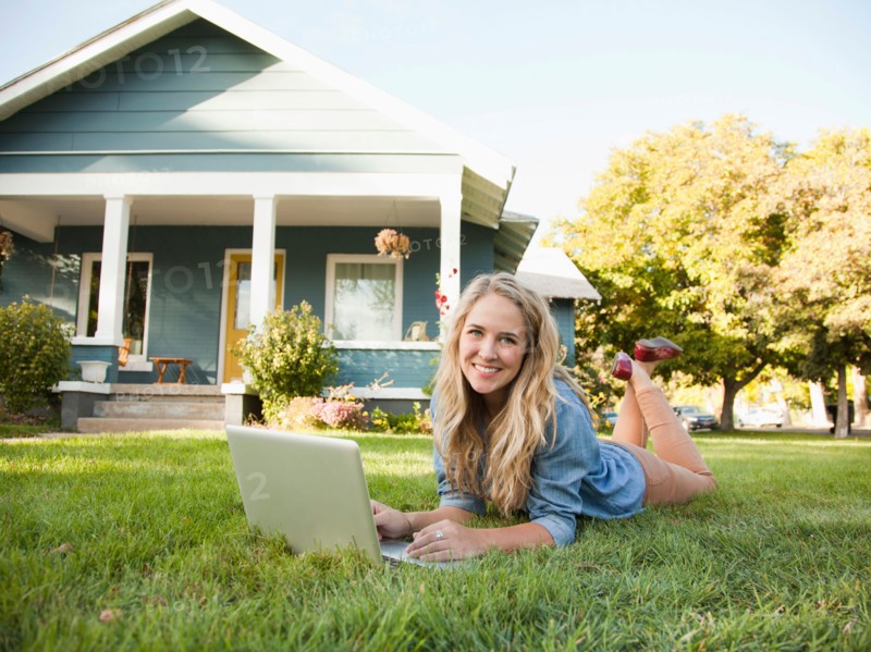 Portrait of young woman lying down on grass with her laptop. Photo : Jessica Peterson