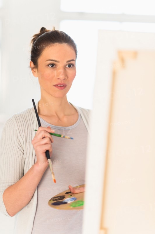 Woman painting at easel.