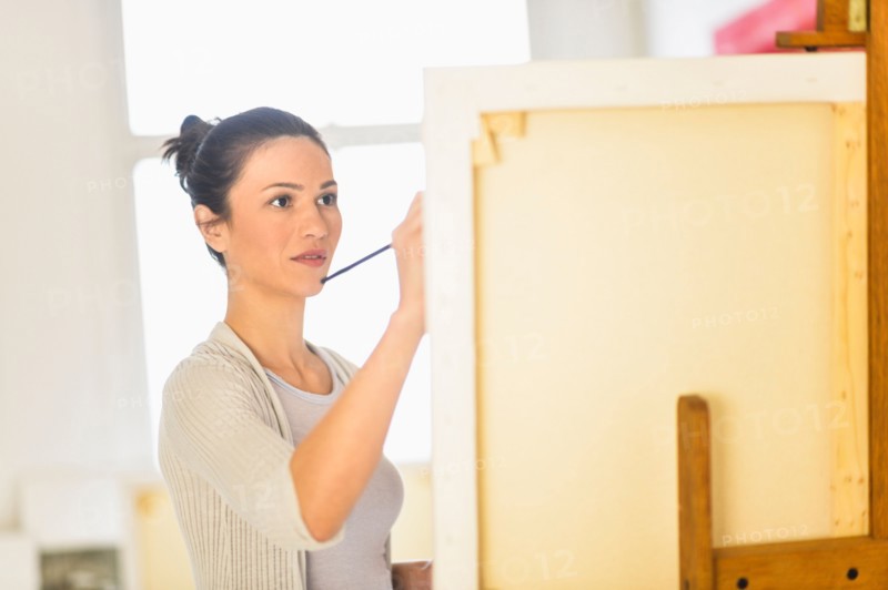 Woman painting at easel.