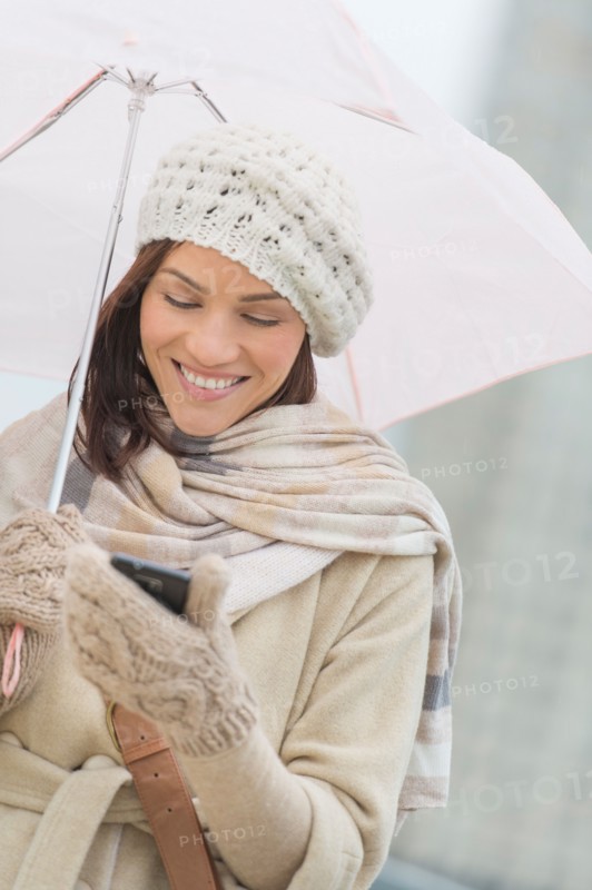Woman with umbrella using phone.