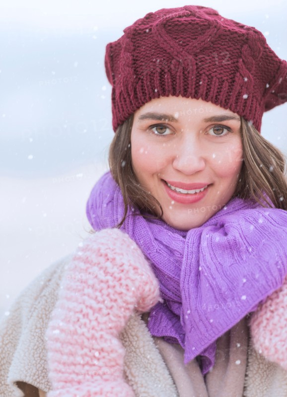 Portrait of young woman wearing knit hat, gloves and scarf.