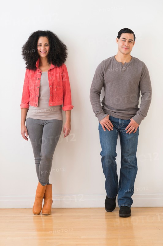 Smiling couple standing against white wall.