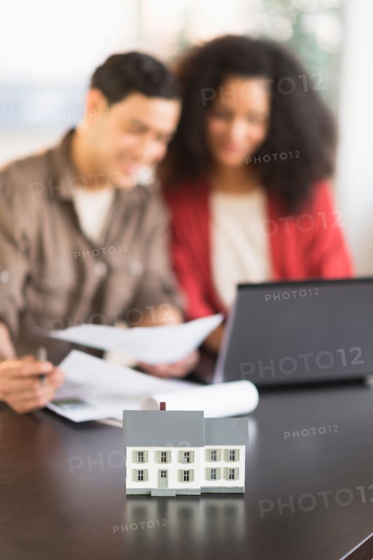 Smiling couple planning home ownership with model home.