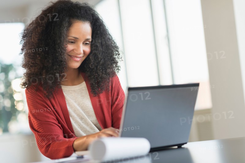 Smiling mid adult woman doing home finances with laptop.