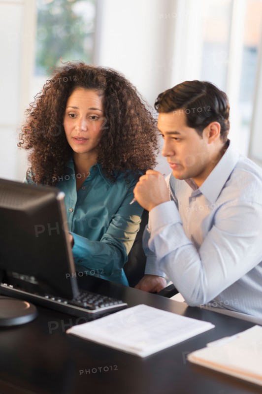 Man and woman working at desk in office.