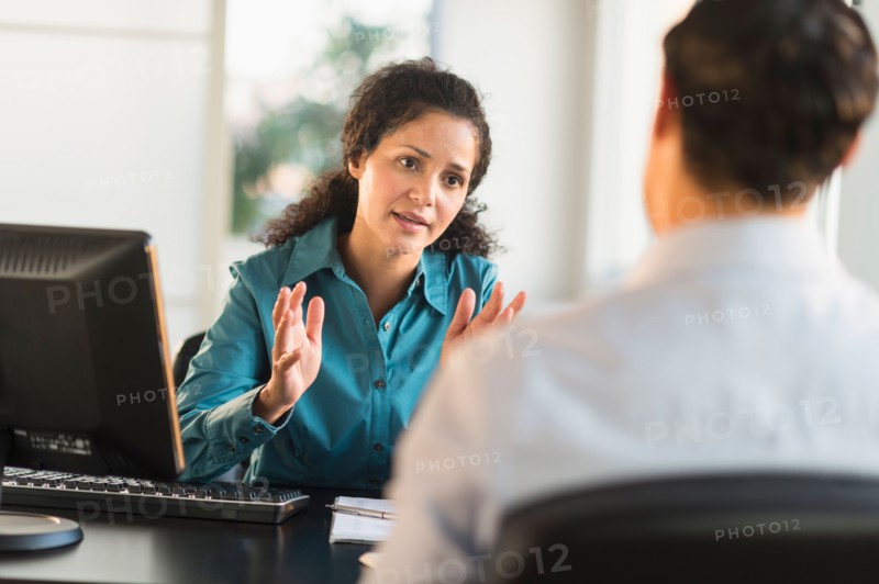 Woman interviewing man at desk.