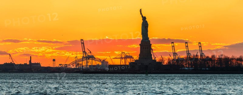 Silhouette of Statue of Liberty at sunset.
