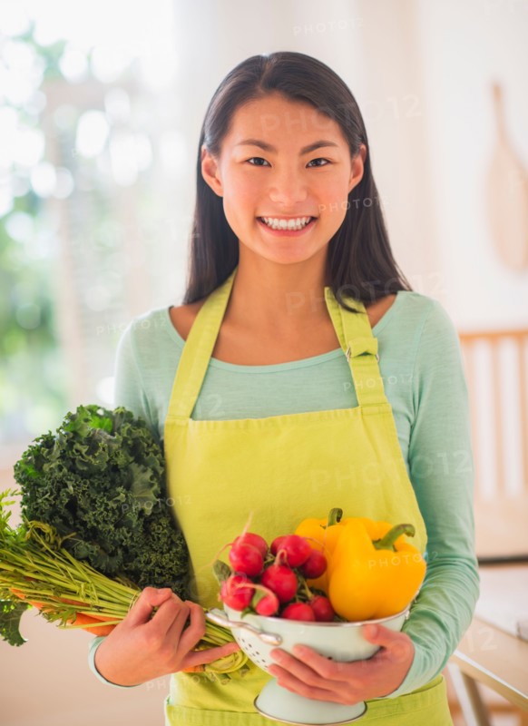Teenage girl with bunch of vegetables in kitchen