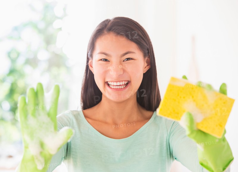 Teenage girl wearing rubber gloves and holding sponge