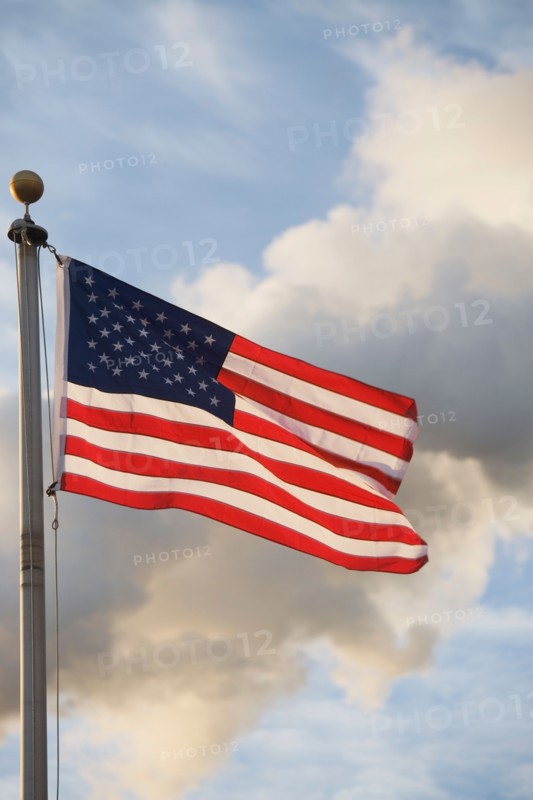 American flag in front of smoke stacks