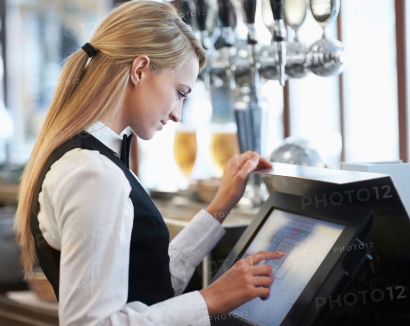 Young waitress using computer at restaurant counter