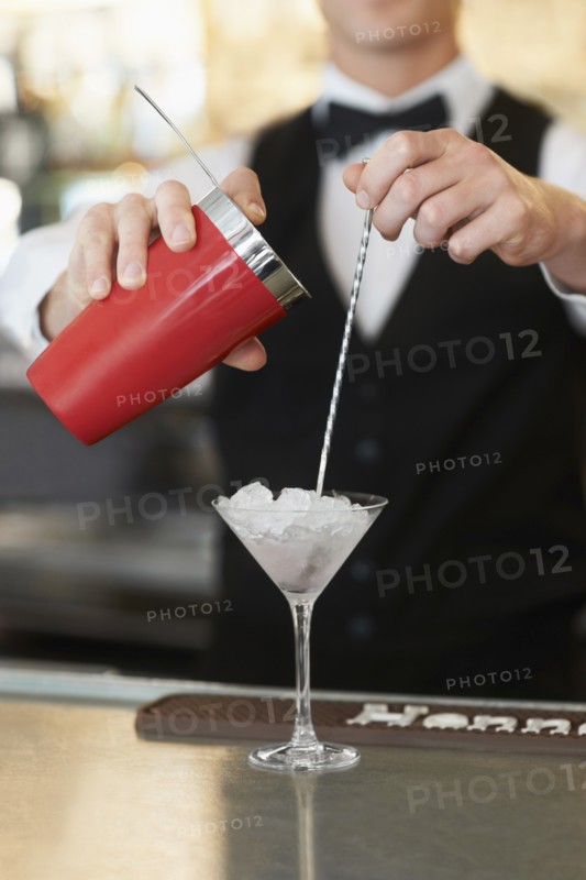 Young bartender pouring cocktail