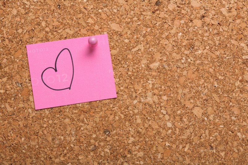 Note paper with drawn heart on corkboard