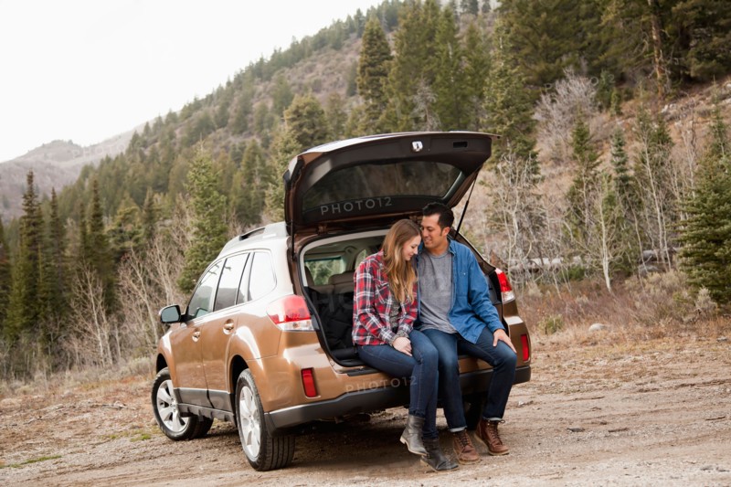 Portrait of young couple sitting in car trunk in non-urban scene