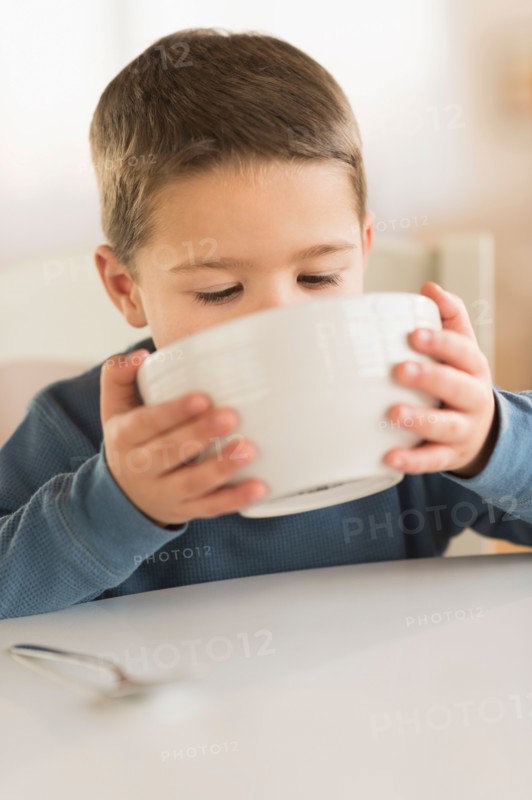 Boy (4-5) drinking from bowl.