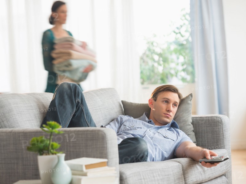 Man lying on sofa watching tv.