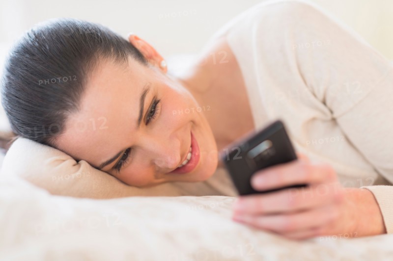 Woman lying on bed and using phone.