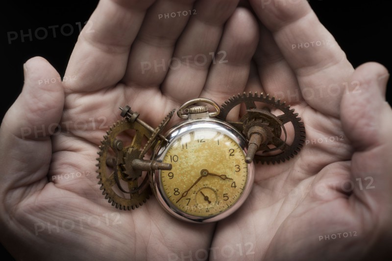Hands holding antique clock and gears.