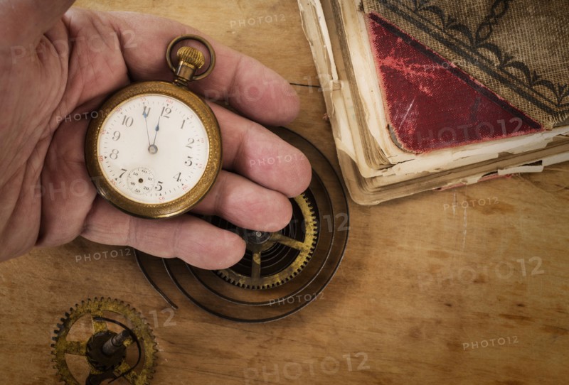 Hands holding antique clock and gears.