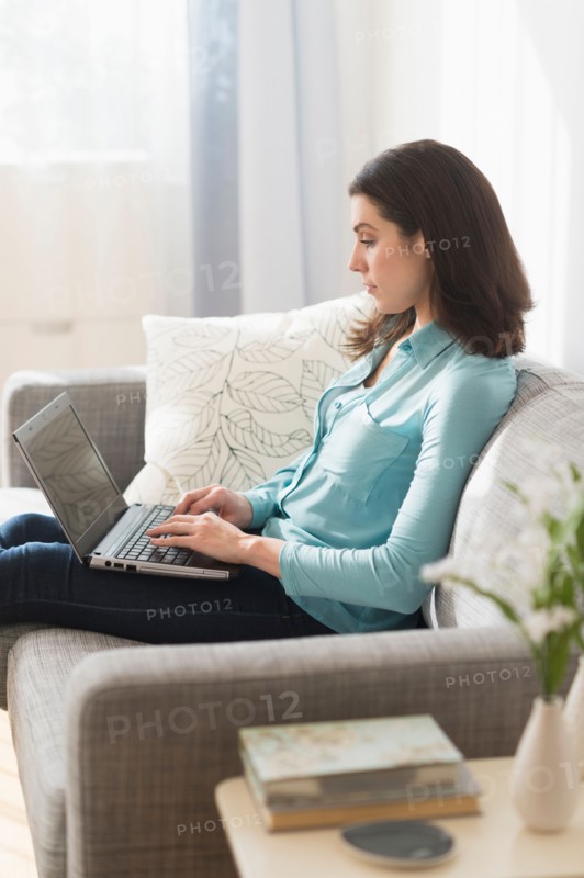 Woman sitting on sofa and using laptop.