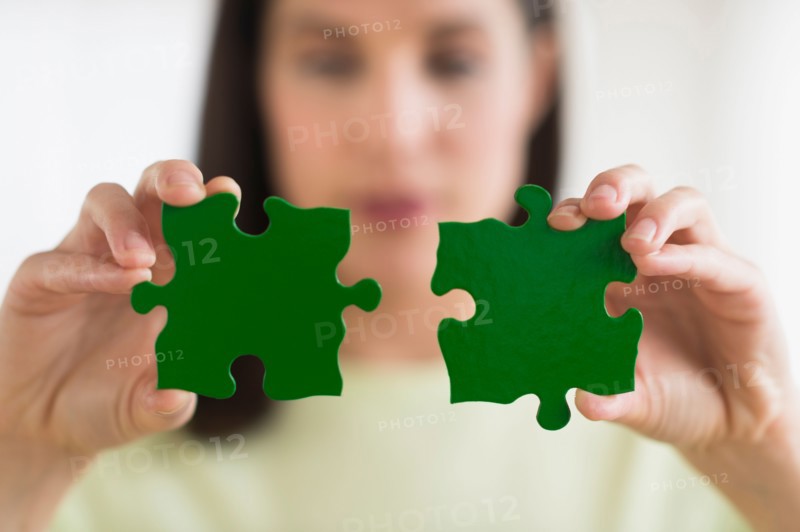 Woman holding green puzzle pieces.