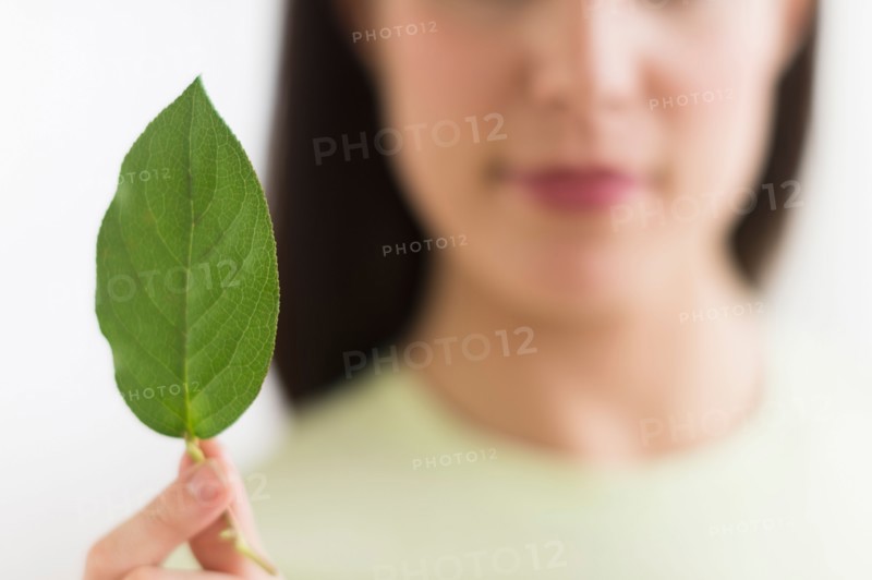 Woman holding green leaf.