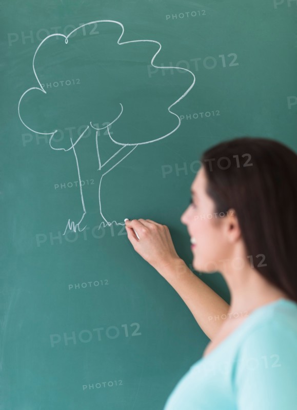 Woman drawing tree on blackboard.