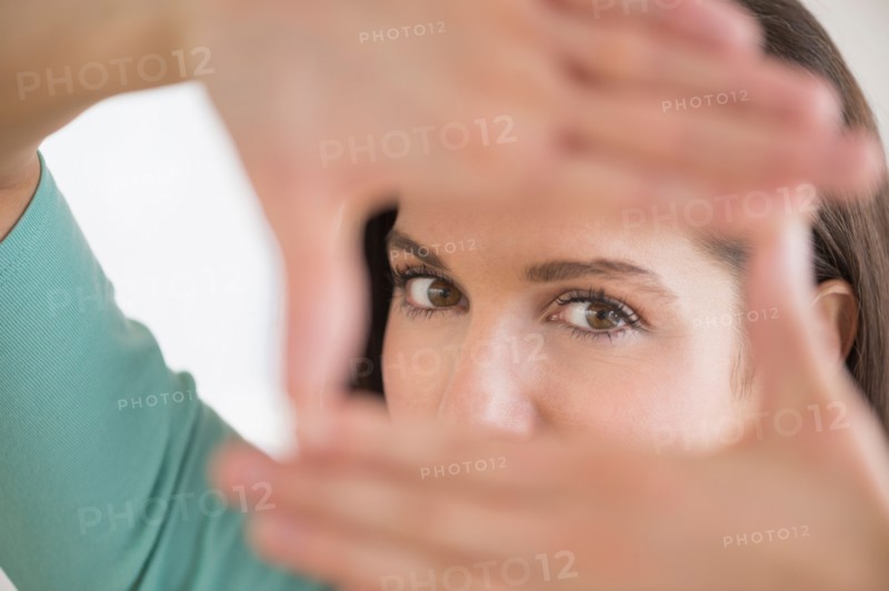 Woman looking at camera through handsframe.